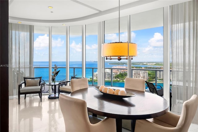 dining room with a wall of windows, a water view, and plenty of natural light