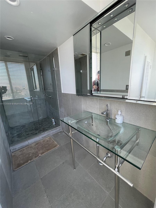 bathroom with tile walls, sink, and a shower with door