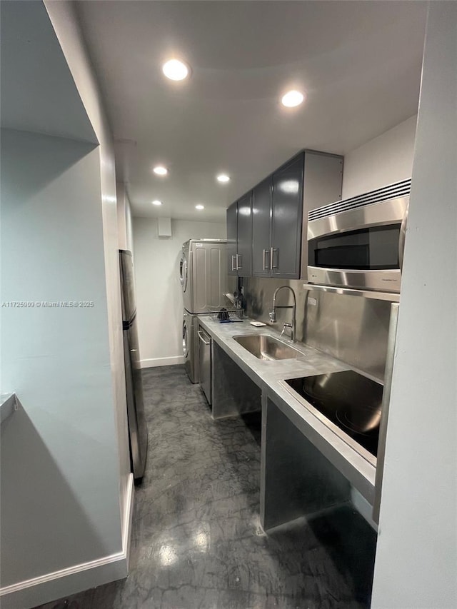 kitchen with black electric stovetop, washer / dryer, sink, and gray cabinetry