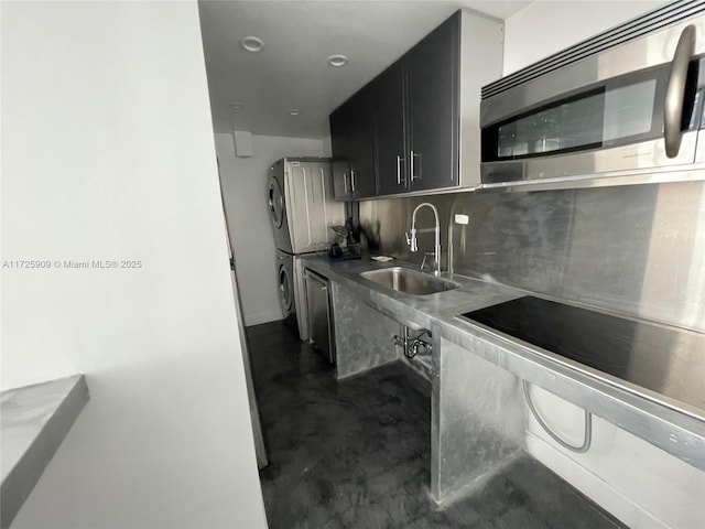 kitchen featuring sink, stainless steel counters, appliances with stainless steel finishes, stacked washer / dryer, and tasteful backsplash