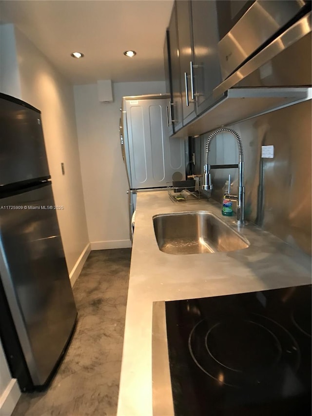 kitchen featuring black fridge, concrete flooring, cooktop, and sink