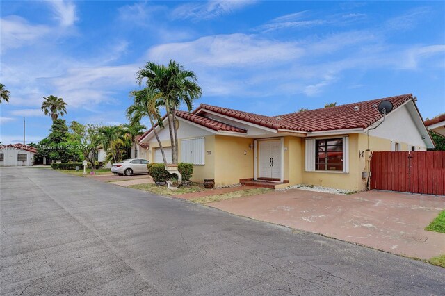 view of front of property featuring stucco siding, a tile roof, a garage, and fence