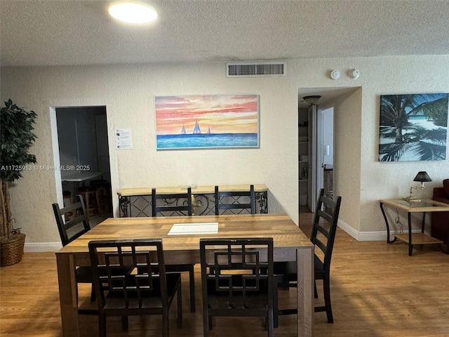 dining space with a textured ceiling and hardwood / wood-style floors