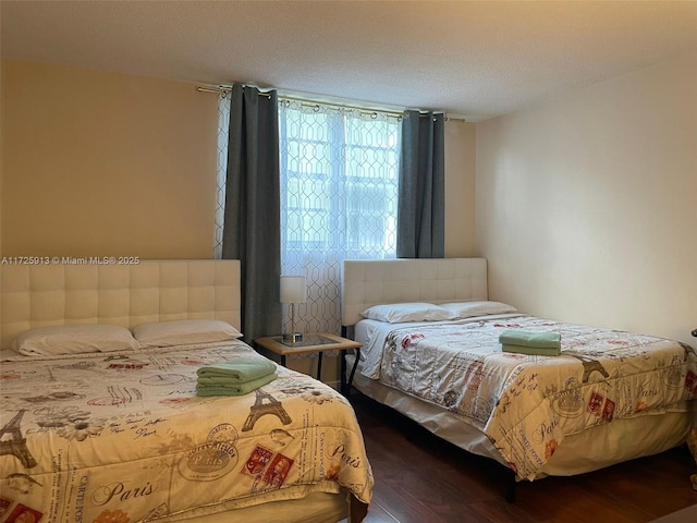 bedroom with a textured ceiling and dark hardwood / wood-style flooring