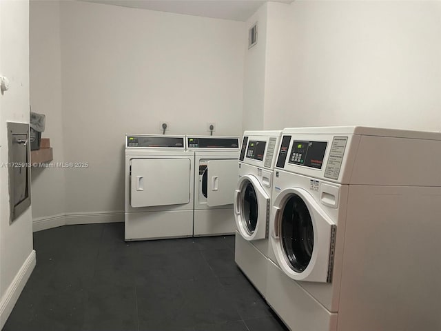 laundry area featuring washer and clothes dryer and dark tile patterned flooring