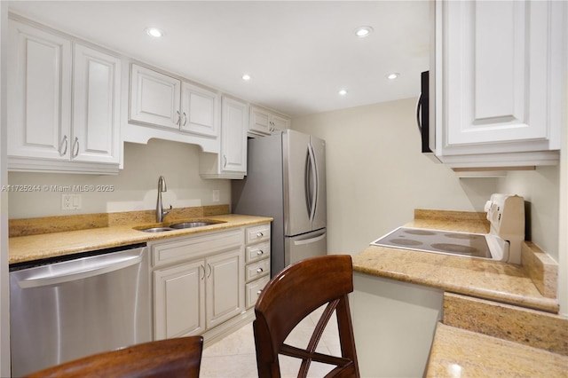 kitchen featuring stainless steel appliances, light tile patterned floors, a breakfast bar, sink, and white cabinetry