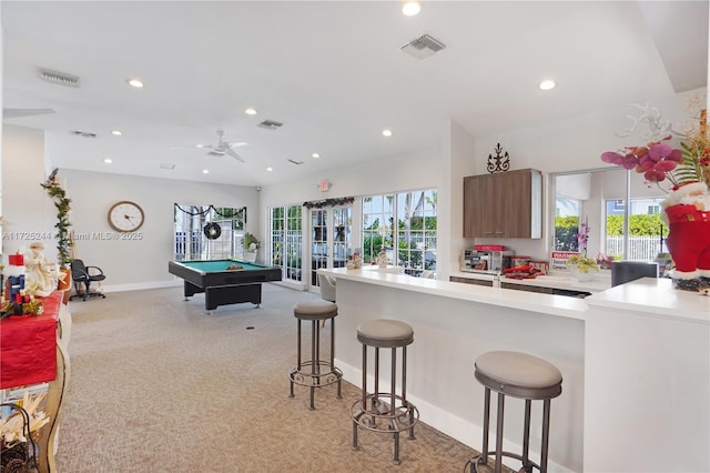 interior space featuring pool table, kitchen peninsula, ceiling fan, and a breakfast bar