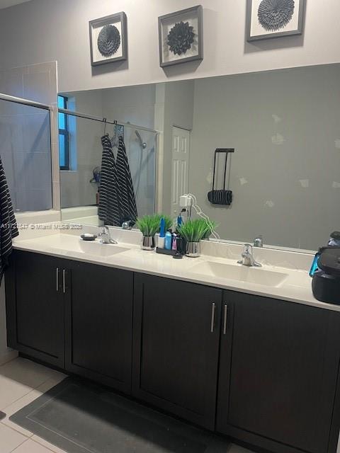 bathroom with a shower with door, tile patterned floors, and vanity