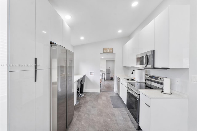 kitchen with sink, white cabinetry, appliances with stainless steel finishes, and lofted ceiling