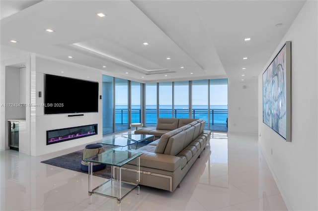 living room with light tile patterned floors, a tray ceiling, and floor to ceiling windows