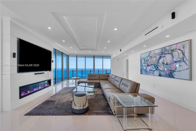 living room with floor to ceiling windows, light tile patterned floors, and a tray ceiling