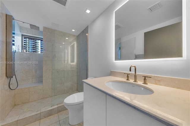 bathroom featuring tile patterned flooring, vanity, toilet, and tiled shower