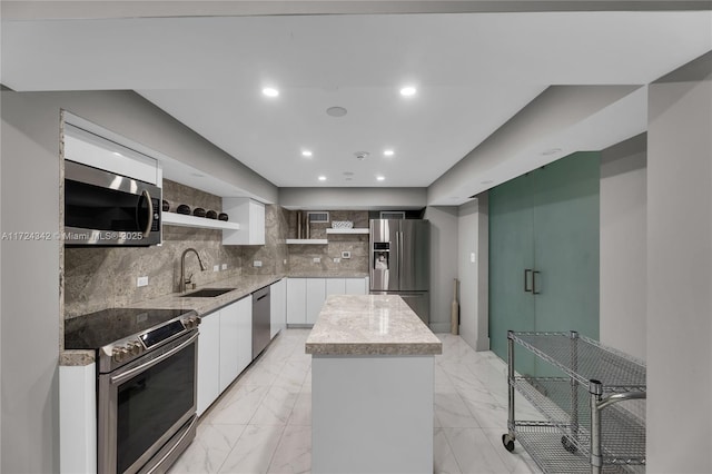 kitchen featuring sink, backsplash, stainless steel appliances, white cabinets, and a kitchen island