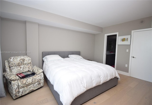 bedroom with connected bathroom and light wood-type flooring