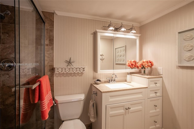 bathroom with a shower with shower door, toilet, vanity, and crown molding