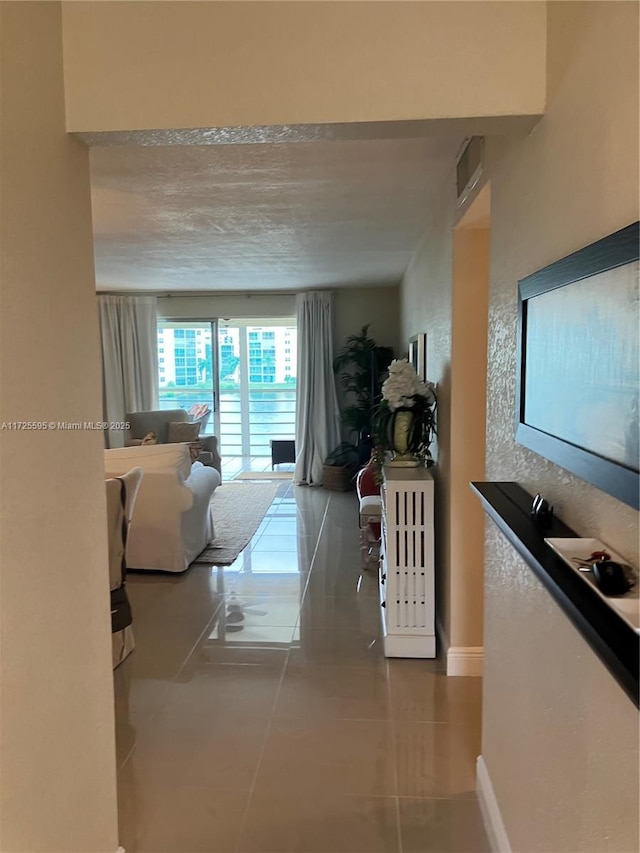 hallway with baseboards, visible vents, and tile patterned floors