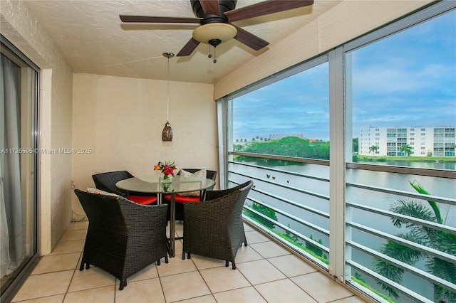 sunroom featuring a water view, plenty of natural light, and a ceiling fan