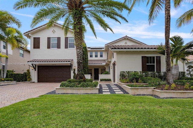 mediterranean / spanish-style house with solar panels, a front yard, and a garage