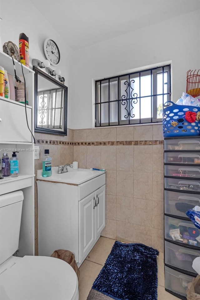 bathroom with toilet, tile patterned flooring, tile walls, and vanity