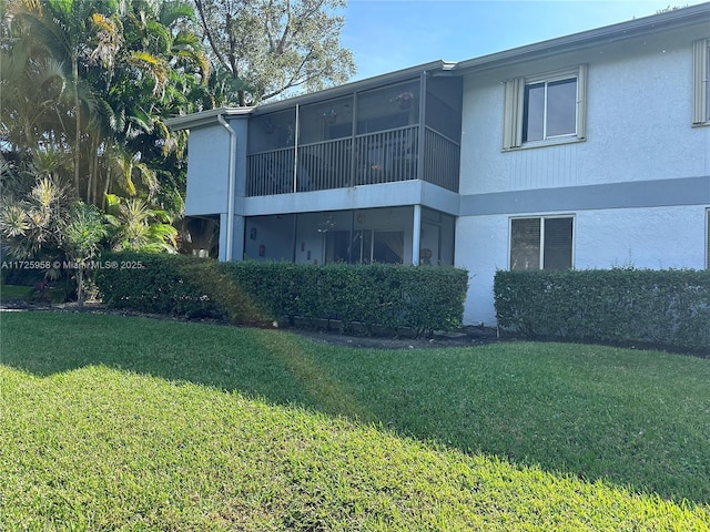 back of property with a lawn and stucco siding