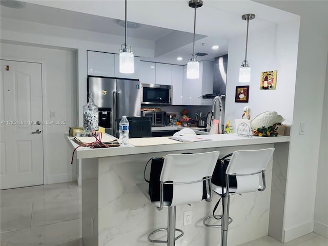 kitchen with a breakfast bar area, stainless steel appliances, kitchen peninsula, pendant lighting, and white cabinets