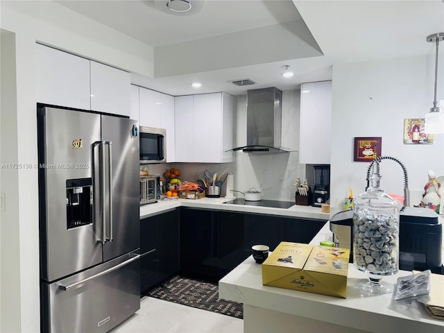 kitchen with stainless steel appliances, white cabinets, wall chimney exhaust hood, backsplash, and hanging light fixtures