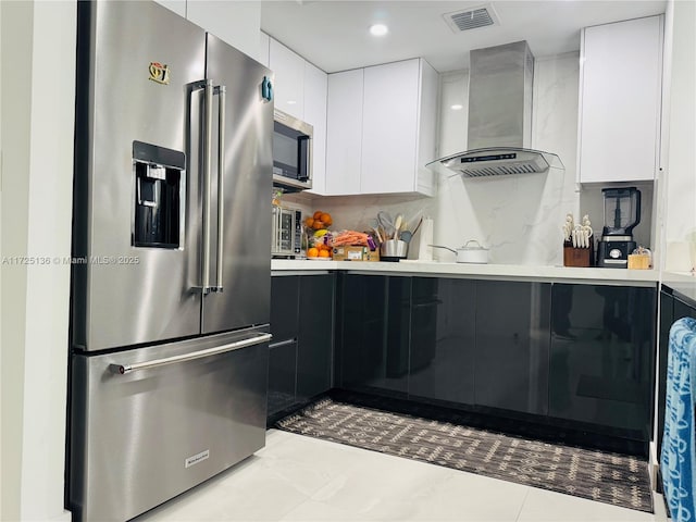 kitchen featuring stainless steel appliances, wall chimney range hood, decorative backsplash, and white cabinetry