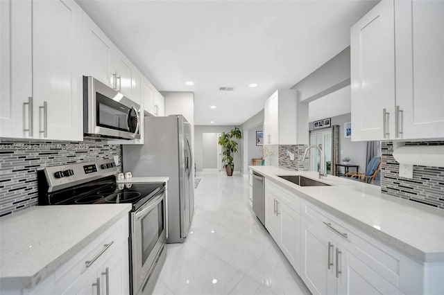 kitchen featuring sink, stainless steel appliances, white cabinetry, and light stone counters