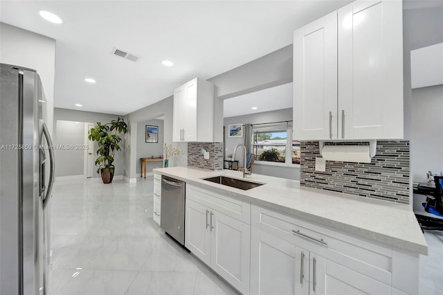 kitchen with sink, white cabinetry, backsplash, light stone countertops, and appliances with stainless steel finishes