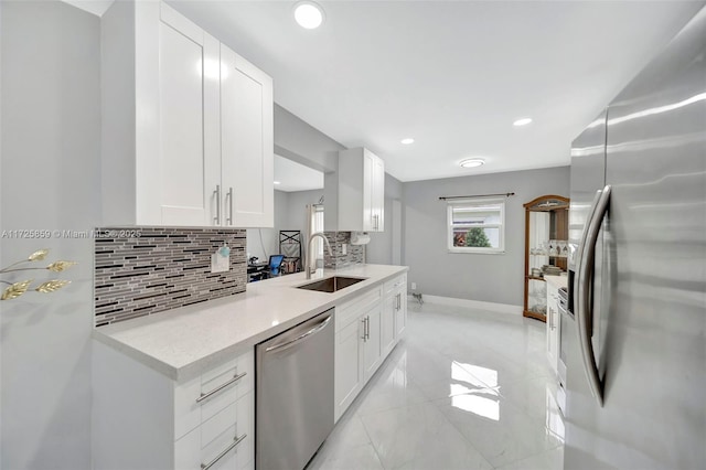 kitchen featuring stainless steel appliances, white cabinets, tasteful backsplash, and sink