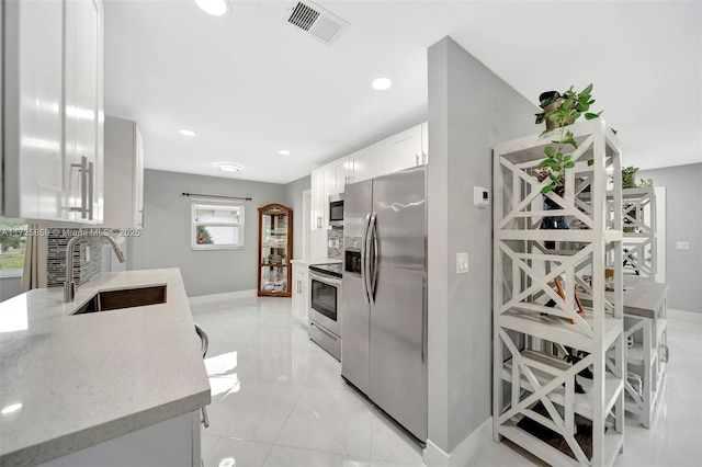 kitchen featuring white cabinets, stainless steel appliances, light stone counters, sink, and tasteful backsplash