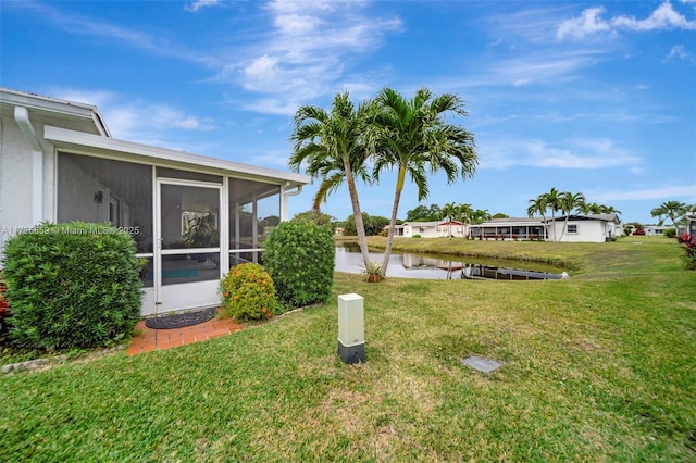 view of yard with a sunroom and a water view