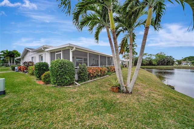 view of home's exterior featuring a yard, a sunroom, and a water view