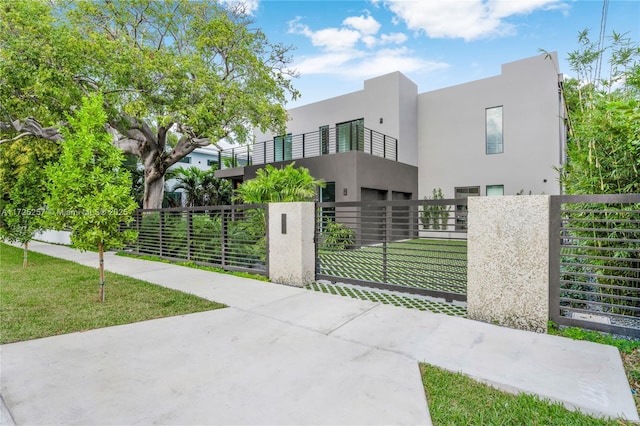 contemporary home featuring a balcony and a front lawn