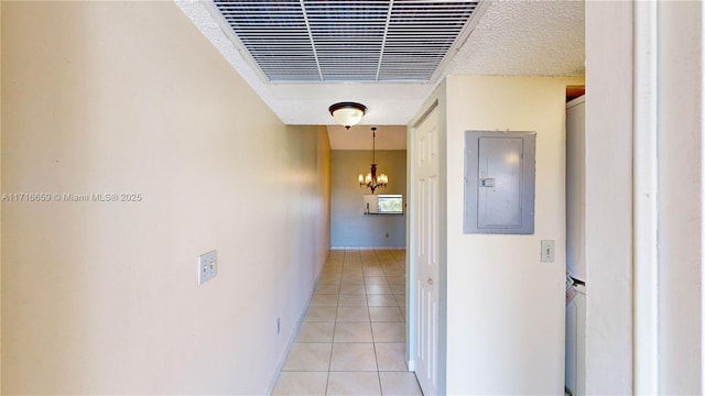 hallway with light tile patterned flooring, electric panel, an inviting chandelier, and a textured ceiling