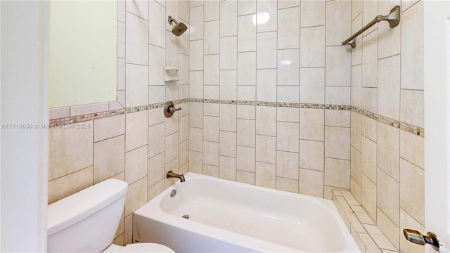 bathroom with tile walls, tiled shower / bath, and toilet