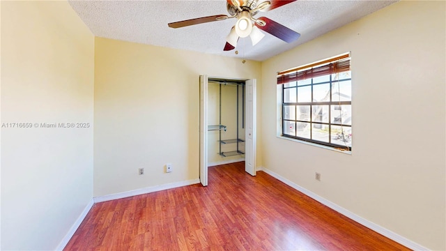 unfurnished bedroom with a textured ceiling, ceiling fan, and hardwood / wood-style flooring