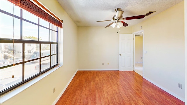 unfurnished room with ceiling fan, a textured ceiling, and light wood-type flooring