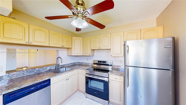 kitchen with sink, light tile patterned floors, stainless steel appliances, light stone countertops, and a textured ceiling