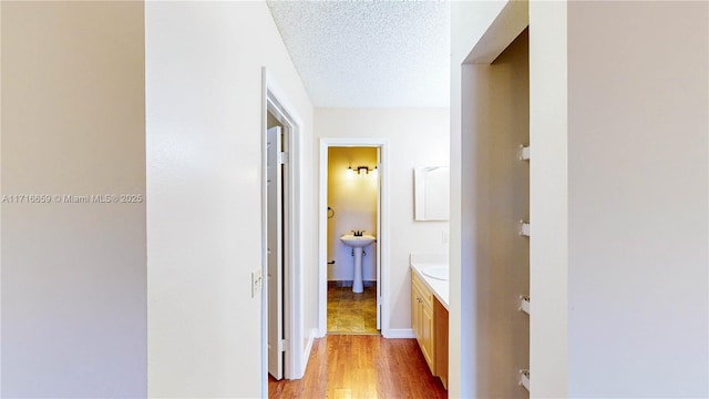 hall featuring a textured ceiling and light wood-type flooring