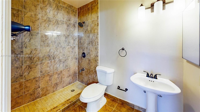 bathroom featuring a tile shower, sink, tile patterned flooring, and toilet