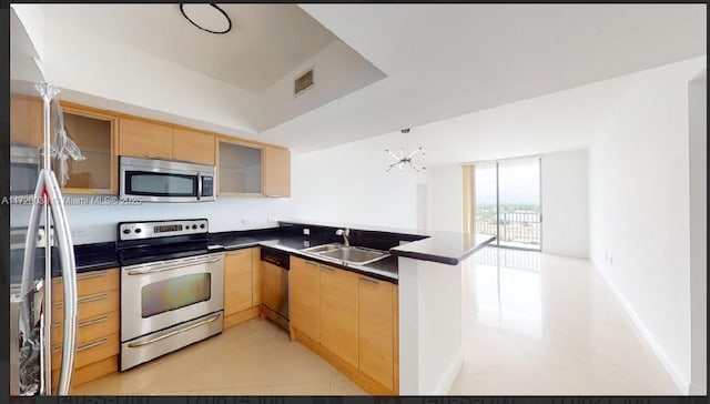 kitchen featuring kitchen peninsula, stainless steel appliances, a notable chandelier, expansive windows, and sink