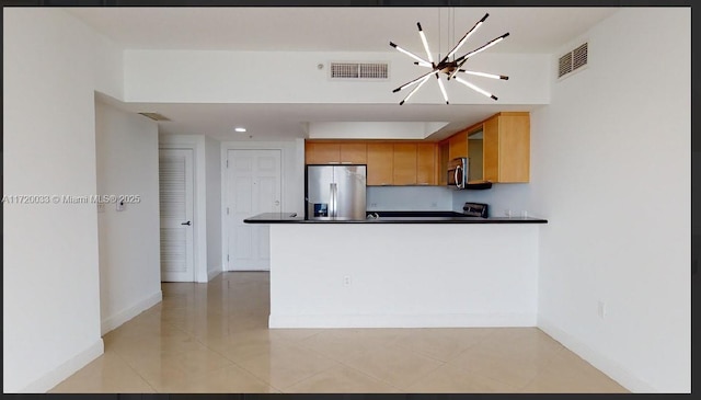 kitchen with kitchen peninsula, appliances with stainless steel finishes, light tile patterned floors, and a chandelier