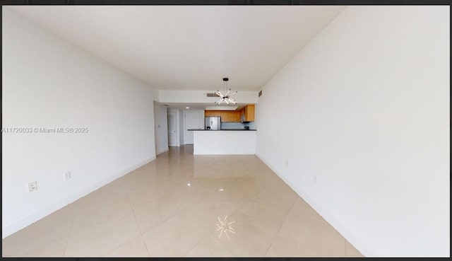 unfurnished living room with a notable chandelier and light tile patterned floors