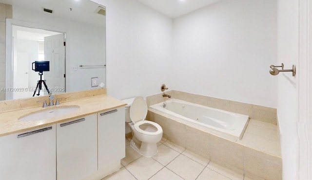 bathroom with a relaxing tiled tub, vanity, tile patterned floors, and toilet