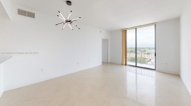 spare room featuring light tile patterned floors, an inviting chandelier, and floor to ceiling windows