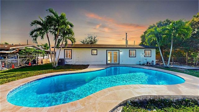 pool at dusk featuring french doors