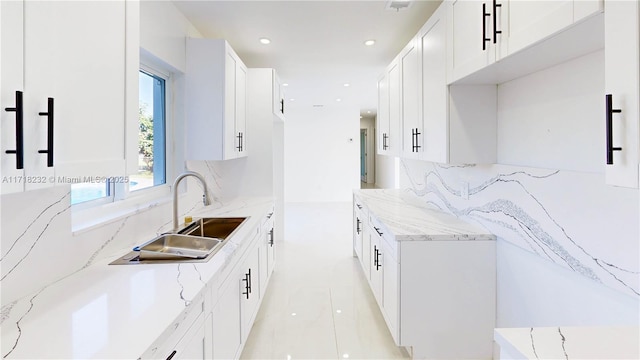 kitchen featuring sink, light tile patterned floors, white cabinetry, light stone countertops, and decorative backsplash