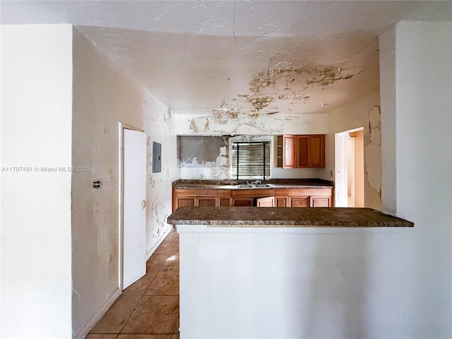 kitchen with sink, electric panel, kitchen peninsula, and tile patterned flooring