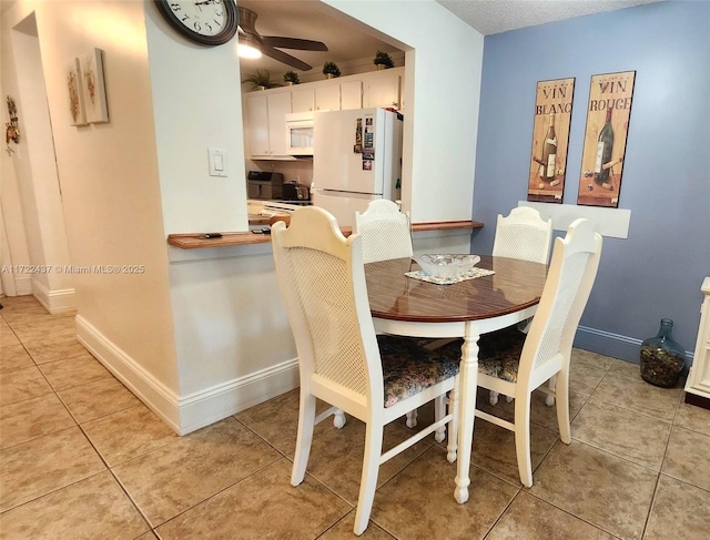 tiled dining space with a textured ceiling and ceiling fan